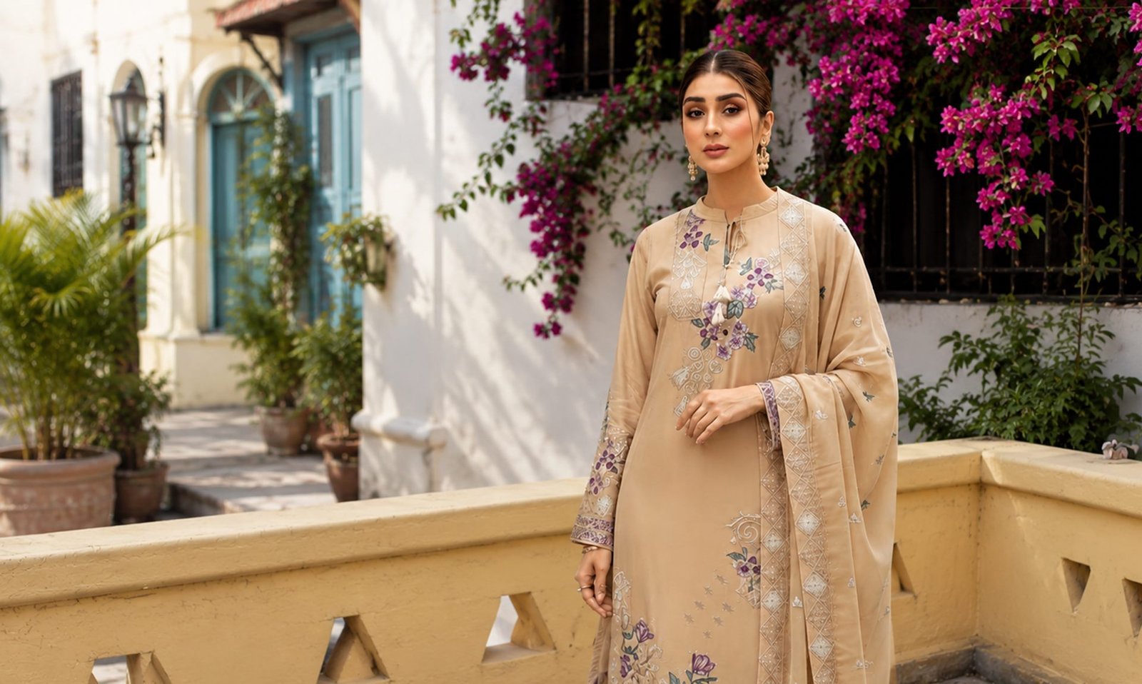 Model in a beige embroidered ZINNEA suit in a sunlit courtyard
